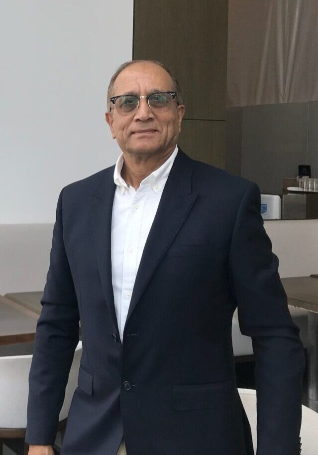 A man in a suit and glasses standing next to a counter.