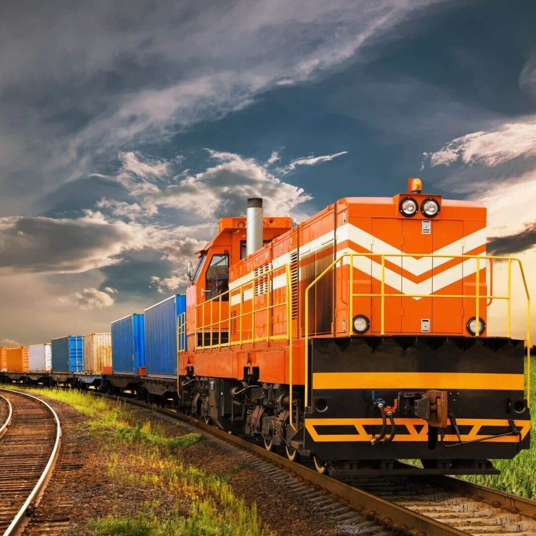 A train is traveling down the tracks under a cloudy sky.